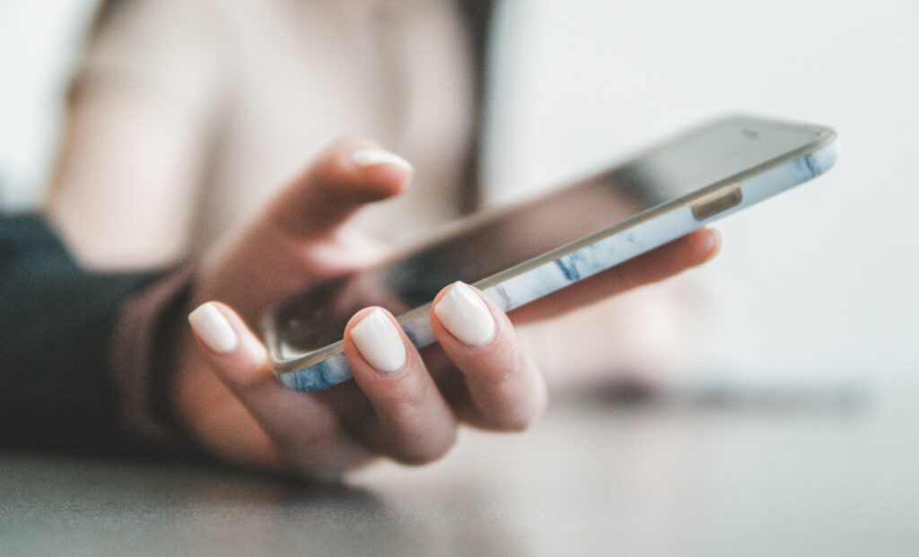 Woman's hand holding a cell phone indicating that she's using fertility tracking devices
