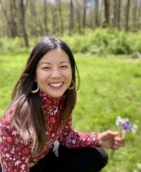 Sharon Yeung from Five Seasons Healing sitting outside holding a flower
