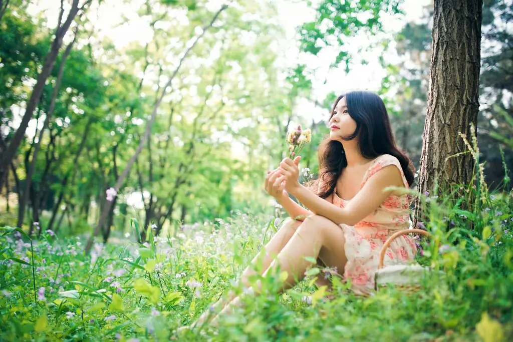 Woman resting in nature holding flower representing holistic support for endometriosis and fertility