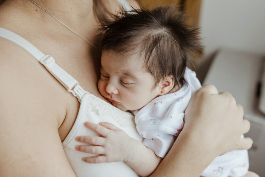 postpartum woman holding baby close to body depicting The First 40 Days: What Chinese Medicine Can Teach Us About Postpartum Recovery